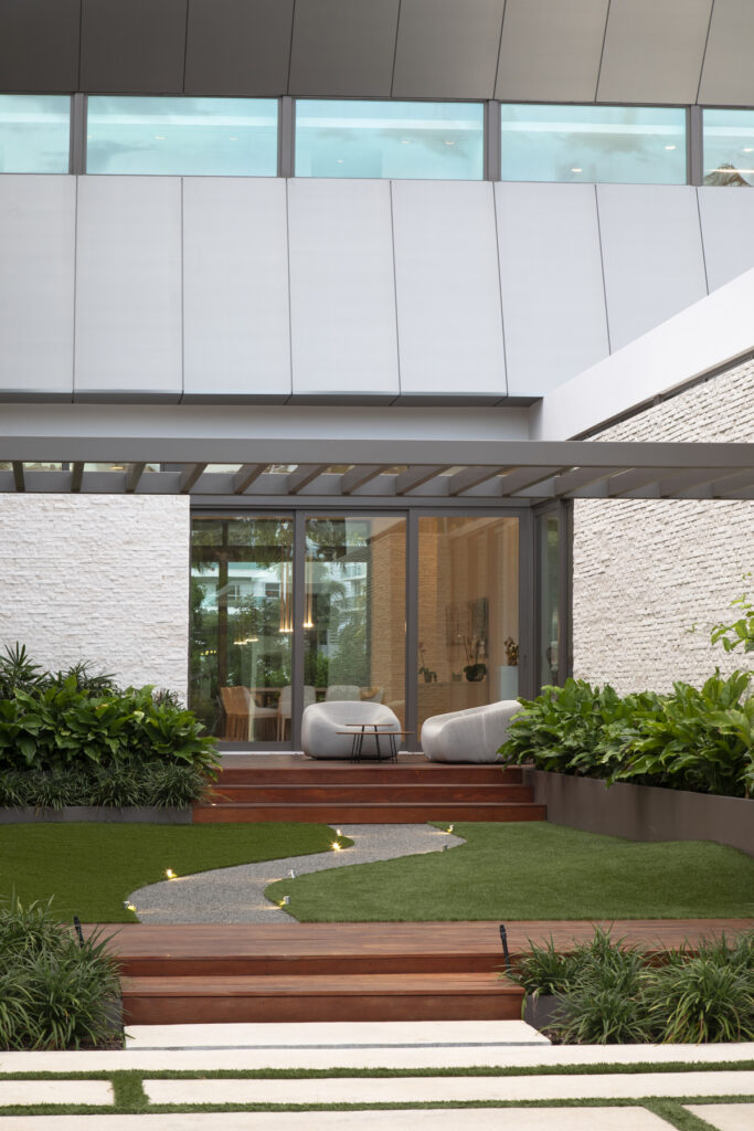Modern Cumaru deck with seating in Bay Area courtyard featuring artificial turf and stone pathway